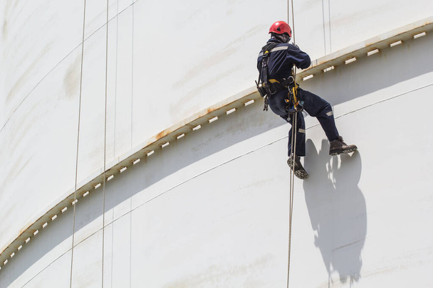 stock-photo-male-worker-rope-access-inspection-thickness-white-storage-tank-shadow